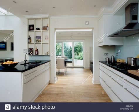 Download this stock image: Wooden flooring in large modern kitchen with doorway to dining room and black granite worktops on white units - E88JRW from Alamy's library of millions of high resolution stock photos, illustrations and vectors. Large Modern Kitchen, Skylight Kitchen, Granite Worktops, Kitchen Furniture Storage, Kitchen Table Centerpiece, White Units, Modern Cupboard, White Kitchen Remodeling, Quartz Kitchen Countertops