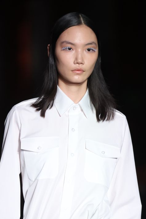 a model walking the runway with pastel blue eyelashes and is wearing a white dress shirt Fashion Week Fall 2023, Fall Beauty Trends, Fringe Styles, Fashion Show Makeup, Prada Runway, Curly Fringe, 2024 Runway, Prada Fashion, Fall Beauty