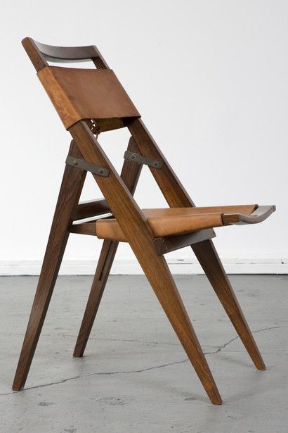 Folding chair with jacaranda frame and leather seat. Designed by Lina Bo Bardi for Studio de Arte Palma, Brazil, circa 1950. (seat height: 16.5") 17.75" L x 16.75" W x 32.25" H / 45.1cm L x 42.5cm W x 81.9cm H. Photo: Joe Kramm/R & Company. Folding Chair Design, Fold Up Chairs, Design On A Budget, Wooden Folding Chairs, Wood Folding Chair, Burle Marx, Outdoor Folding Chairs, Foldable Chairs, Eames Chairs