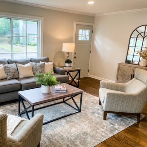 A gray family room with a gray sofa and cream sofa chairs. We used simple décor to stage the space. We added greenery, books, mirror, and cream décor. The items we chose allowed the space to shine. Gray Couch Living Room Accent Chair, Grey Couch And Accent Chair, Grey Couch With Accent Chair, Gray Family Room, Sitting Room Ideas Cozy, Dark Grey Sofa Living Room, Grey Family Rooms, Living Room Redesign, Grey Sofa Living Room