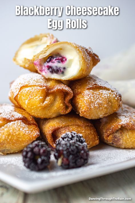 A pile of five Blackberry Cheesecake Egg Rolls on a white square plate with one cut open so you can see soft cheesecake filling and a blackberry