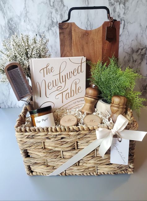 A charming custom wedding gift basket for a beautiful new couple celebrating their special day! Filled with some rustic items for their new home and a cookbook to inspire couples to cook as a team! #weddinggiftideas #weddinggiftideas #weddinggiftbasket #weddinggiftbasketideas #giftsforcouples Newlywed Basket Ideas, Engagement Party Basket Gift, Wedding Gift Ideas For Bride And Groom Presents, Move In Gift Basket Ideas, Newly Wed Gifts Ideas Couple, Housewarming Gift For Couple, Gift Basket For Bride And Groom, Bridal Shower Kitchen Gift Basket, Bride And Groom Gift Basket