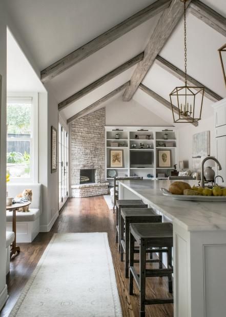 With vaulted ceilings, marble surfaces and crisp white cabinetry, this contemporary kitchen remodeled by Julie Bradshaw seems light and airy. Wood floors and nature-inspired prints add a rustic touch to the space. Farmhouse Fireplace Ideas, Rustic Farmhouse Fireplace, Contemporary Kitchen Remodel, Vaulted Ceiling Kitchen, Open Kitchen And Living Room, Farmhouse Fireplace, Kitchen And Dining Room, Corner Fireplace, White Cabinetry