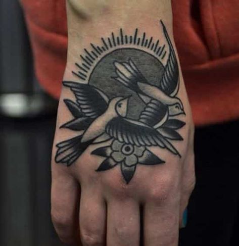 This black and white tattoo features two birds flying in front of a rising sun. The tattoo is strange in that it doesn’t use any bright or warm colors despite its choice of #characters, and so the birds appear like they are flying during night time. Henna Motive, Bird Hand Tattoo, Tattoo Cherry, Tattoo Main, Traditional Hand Tattoo, Bird Tattoo Men, Tattoo Band, Sparrow Tattoo, Sailor Jerry Tattoos