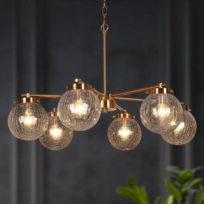 As a source of light and the focal point in any space, chandeliers are experts at fusing function with fashion. With a simple design and distinctive line, this beautiful mid-century modern chandelier features a wagon wheel arm that holds textured glass globe shades downwards and an electroplate gold finish to best match your style. Six E12/candelabra, max 40W bulbs (sold separately) are housed and travel through the textured glass globe shades to diffuse unique light. Brimming with mid-century f Gold Dining Room, Mid Century Modern Chandelier, Gold Globe, Island Chandelier, Wheel Chandelier, Chandelier Metal, Unique Chandeliers, Dining Room Light Fixtures, Wagon Wheel Chandelier