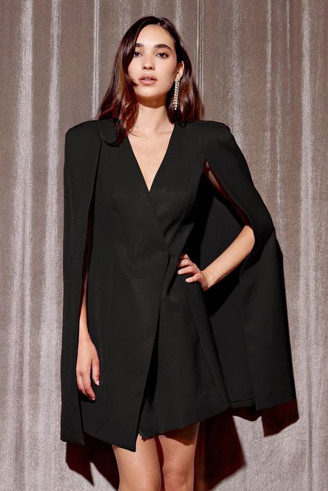 Make a statement in this fabulous Raquel Tux Cape Dress. Show off your drama queen side with this cape dress, featuring an asymmetrical closure. Perfect for your next big event - fun and flirty, you're sure to slay the crowd! Blazer dress Cape Mini V-Neck Lined Length: 34 1/2" Chest: 17" Waist: 15 1/4" Lined Self: 100% Polyester Lining: 100% Polyester Hand wash cold with similar colors. Do not tumble dry, iron, or dry clean. Model is wearing a size S  Style #: F2310D5693 Cape Blazer, Prom Outfit, Dress Cape, Clothing Reference, Womens Suits Business, Drama Queen, Tuxedo Dress, Cocktail Attire, Dresses Xxl