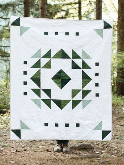 The Evergreen Quilt Pattern showcases a modern ombre design that pops against a crisp white background. Deceptively easy and versatile, the multi-sized quilt pattern uses half-square triangles for the center block and builds on it with stripes to com... Sage Green Quilt Patterns, Modern Simple Quilt Patterns, Green And White Quilt, Green Quilts Ideas, Neutral Quilts Ideas, Geometric Quilt Patterns, Simple Quilt Patterns, Ombre Quilts, Deco Quilt