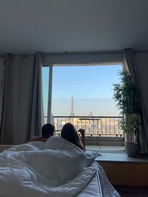 Couple laying in bed looking at the balcony where you can see the eiffel tower. Honeymoon In Paris Aesthetic, Paris Aesthetic Honeymoon, Caring Man Aesthetic, Europe Honeymoon Aesthetic, Work Couple Aesthetic, France Couple Aesthetic, Hotel Aesthetic Couple, Paris Honeymoon Aesthetic, French Couple Aesthetic