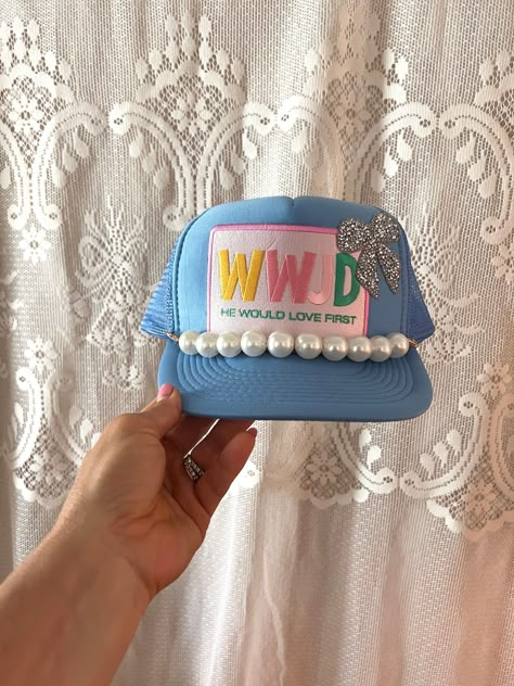 Inspire and uplift with this beautiful Blue "WWJD - He Would Love First" Trucker Hat! Featuring a colorful embroidered patch with the acronym "WWJD" (What Would Jesus Do) and the powerful message "He Would Love First," this hat is perfect for expressing your faith with a stylish twist. The addition of a sparkling glitter bow and a row of elegant pearls adds a unique and charming flair.  This hat along with all of my other trucker hats are handmade, one of a kind and made to order. Designed for b Trucker Hat Charms, Christian Trucker Hats, Trucker Hats With Patches Diy, Trucker Hat Patches, Patch Trucker Hat, Cute Trucker Hats, Trucker Hats With Patches, Trucker Hat Ideas, Trucker Hat Designs