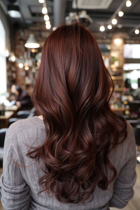 Woman with long, wavy, auburn hair in a cozy, modern salon. Chestnut Red Hair With Highlights, Long Brown Hair Transformation, Copper Mahogany Hair Color, Chocolate Copper Hair Color, Rose Brown Highlights, Brown Hair Ideas For Fall, Chocolate Cherry Balayage, Chocolate Red Brown Hair, Brown Reddish Hair