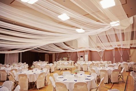 Tulle ceiling                                                       … Lds Wedding Reception Cultural Hall, Gym Wedding Reception, Tulle Ceiling, Wedding Traditions Game, Lds Weddings Reception, Reception Timeline, Wedding Reception Timeline, Wedding Reception Hall, Wedding Draping