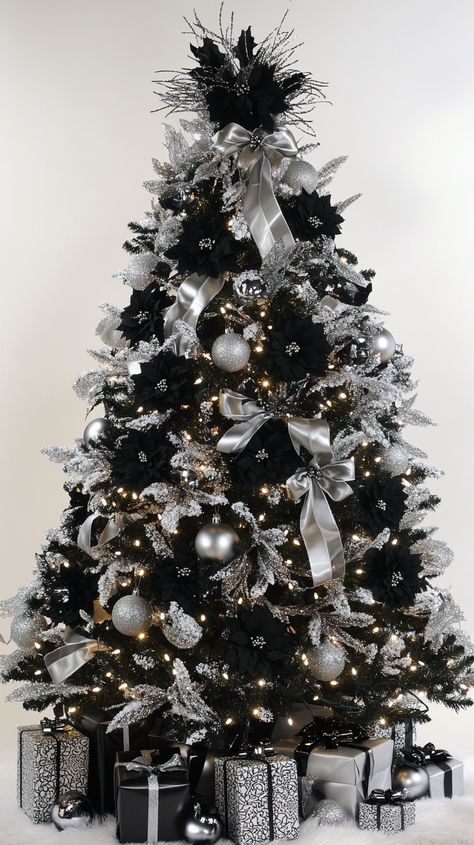 Elegant black and white Christmas tree adorned with silver ribbons, black flowers, and presents underneath. Silver White Black Christmas Tree, Christmas Trees With Black Ornaments, Black And White Christmas Tree Decorations, Black Gold White Christmas Tree, Christmas Tree With Silver Decorations, Black White Silver Christmas Tree, Black White And Silver Christmas Tree, Black Tree Decorating Ideas, Red Black And White Christmas Tree