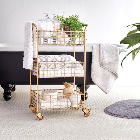 If vanity space is scarce and you have minimal floor real estate to fit your necessities, try a three-tier wire cart. The gold finish on this one adds a touch of luxe while the slightly wavy weave adds a little extra decoration. Plus, the wheels allow the cart to hold things you might for other rooms in your home. #marthastewart #organization #declutteringtips #homedecorideas #details Bathroom Storage Cart, Ikea Molger, Gold Wire Basket, Bathroom Cart, Rangement Makeup, Gold Bar Cart, Bar Cart Styling, Smart Tiles, Cart Decor