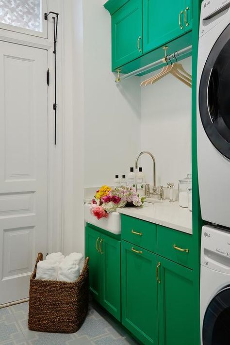 Emerald green laundry room cabinets are accented with antique brass pulls and white quartz countertop finished with a farmhouse sink paired with a polished nickel deck mount faucet. Emerald Green Laundry Room, Green Laundry Room Cabinets, Green Laundry Room, Transitional Laundry Room, Pink Laundry Rooms, Farmhouse Sink Faucet, Green Laundry, Room Storage Diy, Farmhouse Laundry Room