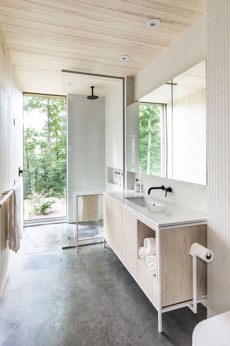 Concrete stretches across the bathroom floor into the shower, where a floor-to-ceiling window frames the great outdoors. A simple palette of concrete, plywood, and keystone white mosaic tile gives the bathroom a clean look. #dwell #canada #prefabhomes #moderncabins Mount Tremblant, Quebec Summer, Tremblant Quebec, White Mosaic Tile, White Mosaic Tiles, Cedar Cladding, House Shutters, Prefab Cabins, Compact House