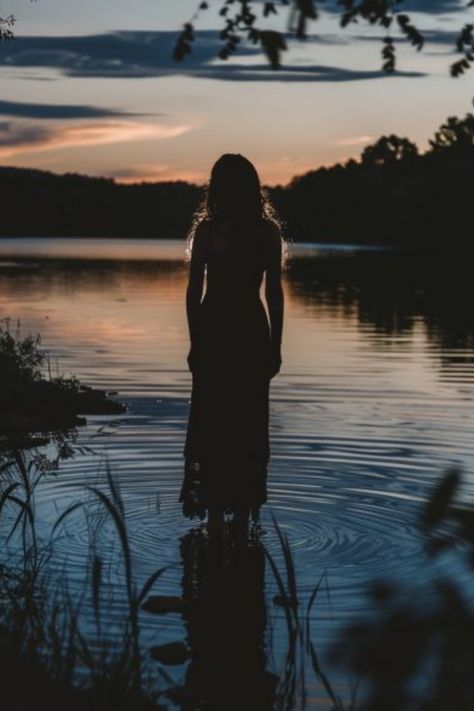 Silhouetted person standing in calm water with reflections at sunset. Nature Photography Professional, Lake Aesthetic Photoshoot, Summer Evening Photoshoot, Moody Lake Photoshoot, Moody Water Photoshoot, Aestethic Photoshoot Ideas, Creek Photoshoot Ideas, Cute Summer Photoshoot Ideas, Cool Photoshoot Ideas Creative Unique