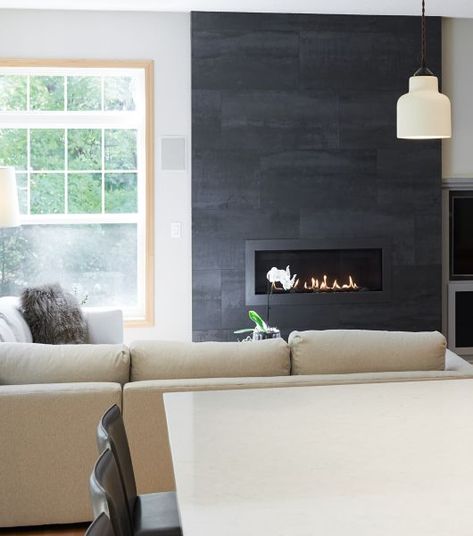 Living room with a fireplace with black large-format tile. White Tiled Fireplace Ideas, Tile Around Fireplace, Black Tile Fireplace, Fireplace Chimney, Living Room With A Fireplace, Tiled Fireplace, Grey Fireplace, Slate Fireplace, Fireplace Tiles