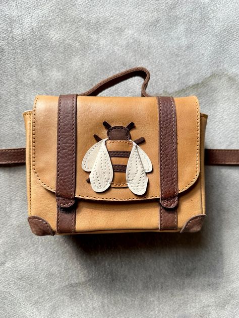 We're suckers for cute. And for serious craftsmanship. So we are truly delighted to offer pieces by the Dutch maker Donsje. Sustainably sourced, fair trade, made by hand and made to last. Darling leather accessories that make everyone smile. Little leather "Bee" fanny pack is 6 x 4 1/2 inches with a belt that adjusts from 22 - 26 inches. Bee Bag, Bee Purse, Leather Accessories Handmade, Cute Crossbody Bags, Leather Craft Projects, Sweet Accessories, Leather Bag Pattern, Animal Bag, Sewing Leather