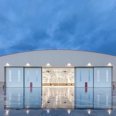 Introducing the impressive Warm Storage Hangar. 🚁 We are proud to have partnered with the Fort Wainwright Aviation Task Force in creating this state-of-the-art facility that seamlessly blends with the historic charm of the Ladd Field National Historic Landmark District. With its steel framed bowstring trusses and concrete foundation, this 56,660 SF hangar offers a climate-controlled haven for seven rotary wing aircraft. exploredesign.com #Explore #Design #Architecture #Alaska #Aviation Airplane Hangar Design, Aircraft Hangar Design, Hangar Design, Concrete Foundation, Aircraft Hangar, Airplane Hangar, Green Houses, Innovation Centre, The Fort