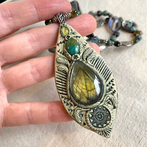 "Immerse yourself in the allure of this elaborate, one-of-a-kind necklace featuring a flashy blue-green labradorite gemstone set with polymer clay (fimo) on a wood backing. A small bright oval turquoise and a tiny peridot are intricately inlaid in the clay, creating a captivating pendant. Baked in a small oven, the clay pendant is then meticulously painted and washed, revealing the exquisite details within. The beaded necklace showcases beautiful pawa shells, green tourmaline flat chips, small r Dry Clay Jewelry, Clay And Stone Jewelry, Polymer Clay Goddess Pendant, Baking Polymer Clay, Polymer Clay Painting, Polymer Clay Gifts, Goddess Necklace, Magical Jewelry, Polymer Clay Necklace