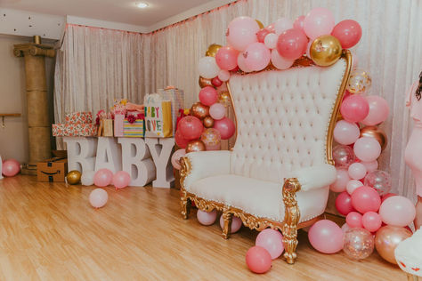 White throne chair with gold arm accents against velvety white built-in curtain drapery. Pink and Gold balloon arch frames throne. In the corner is an iconic white gift table with bold baby lettering at the base. Baby Shower Mom Chair, Baby Shower Seating, Baby Shower Sitting Area For Mom, Baby Shower Chair For Mom, Baby Shower Chair, Queen Chair, Shower Seat, Throne Chair, Lake County