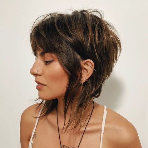 This fall haircut offers a bold, playful vibe with its edgy shaggy bob and wispy bangs. The choppy layers provide volume and movement, creating a dynamic style perfect for those looking to make a statement. The dark roots with lighter tips add contrast, enhancing the haircut’s rebellious charm. Piecy Bob Hairstyles, Choppy Bob Hairstyles For Fine Hair Short Styles, Shoulder Length Choppy Layers, Short Hairstyle Women Round Face Bob Haircuts Thick Hair Straight, Short Edgy Bob, Shaggy Haircuts With Bangs, Choppy Bob Hairstyles With Bangs, Short Edgy Hairstyles, Shaggy Bob With Bangs