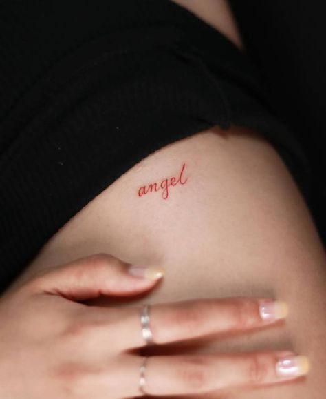 Tattoo of the word "angel" in red ink located on the Red Tattoo Writing, Red Ink Name Tattoo, Red Angel Wings Tattoo, Word Angel Tattoo, Red Angel Tattoo, Red Ink Word Tattoo, Angel Tattoo Word, Red Ink Neck Tattoo, Angel Word Tattoo