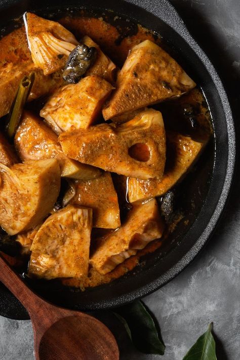 Overhead shot of Young Jackfruit Curry in a black pot on a grey surface. The jackfruit is cut in triangular pieces and a wooden spoon is in the bottom left corner. Sri Lankan Curry, Jackfruit Curry, Parsley Salad, Asian Grocery Store, Sri Lankan Recipes, Fruit Peel, Asian Grocery, Unusual Plants, Curry Leaves