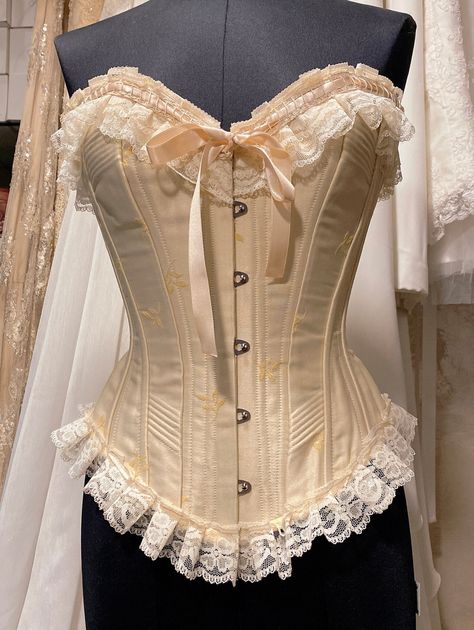 Victorian Overbust Corset, made in ivory embroidered silk satin, silk satin corded panels and ivory silk satin lining, with additional lace trimmings and ribbons. This corset is inspired by the victorian silhouette but made to be worn as a show stopping piece by a history lover.  Offers up to 10 cm waist reduction.  Plastic boning and metal boning available, metal busk.  This beauty is available in a number of different colours and fabrics, with or without lace, with or without cording panels, m Vintage Corsets, Corset Victorian, Beige Corset, Victorian Corset Aesthetic, Victorian Corsets, Silk Corset, Creative Corset Designs, White And Gold Corset, Vintage Corset Outfit