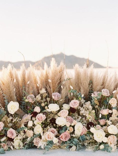 pampas grass and rose-filled floral installation Pampas Grass Wedding Bouquet Spring, Pampas Flower Wall, Dusty Rose Pampas Wedding, Pampas And Pink Flowers, Spring Pampas Grass Wedding, Pampas And Roses Centerpiece, Matrimonio Pampas, Pampas And Roses, Pampas Grass Backdrop