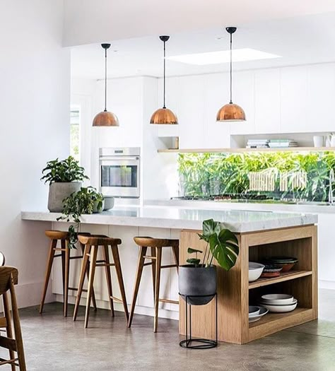 white kitchen, cement floors, copper pendant lighting, white countertops, green plants, wood barstools Adore Magazine, Dapur Skandinavia, White Wood Kitchens, Kitchen Island Bench, Kursi Bar, Kitchen Lights, Kitchen Light, Scandinavian Kitchen, Trendy Kitchen