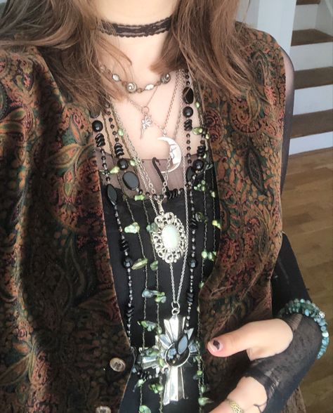 A mid-size person/girl wearing a black lace tank top, a green/red/orange patterned wide open waistcoat over it, a black ripped tights top under it, black corduroy pants, black platform dr. Martens and multiple crystal rings and bracelets. 	The person is also wearing multiple silver necklaces; one in form of a skull, a cross, and one in form of a moon, a long black bead and an even longer green bead necklace and a black lace choker. Whimsy Goth Outfit Men, Cupidcore Aesthetic Outfit, Whimsigoth Fashion Masc, Mens Whimsigoth, Eco Goth Aesthetic, Alt Outfits Pants, Green Necklace Outfit, Masculine Whimsigoth, Funky Waistcoat