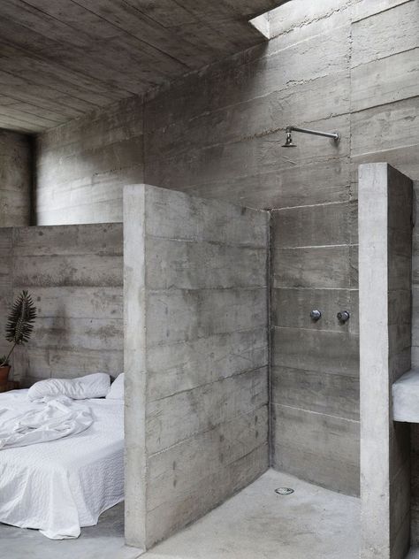 A stickler to the minimalistic principle of the Brutalist Style as only concrete half walls separate the bed space from the shower area and the shower area from the sink. The concrete ceiling also only partially covers the space. The open layout gives the very airy feel to the space, which would otherwise may feel claustrophobic. #minimalist #minimalism #brutalism #simple Ludwig Godefroy, Fortress House, Concrete Bathtub, Brutalist Interior, Concrete Interiors, Half Walls, Concrete Bathroom, Concrete Houses, Concrete Walls