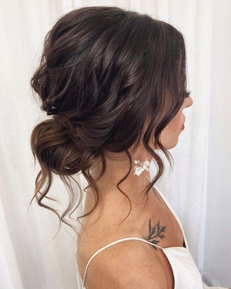 Charming Tousled Bun for Brides Flowy Wedding Hairstyles Loose Updo, Bridesmaid Low Messy Bun, Messy Bun Evening Hair, Low Bun Bridesmaid Hair Front View, Low Messy Bun Bridesmaid Hair, Wedding Hair Messy Low Bun, Low Messy Bun Bridal Hair, Loose Wavy Updo, Wedding Brunette Hair