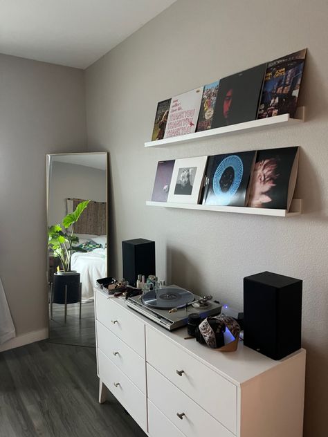 Corner of bedroom with grey floors. Record player on white dresser. Records displayed on wall on while ikea shelves. Gold frame mirror in corner with plant in black plant stand. Wall Decor Bedroom Men Room Ideas, Tv In Room, Street Style Bedroom, Street Style Room, Mens Room Decor, Mens Bedroom Decor, Vinyl Room, Apartment Living Room Design, Decorating Home