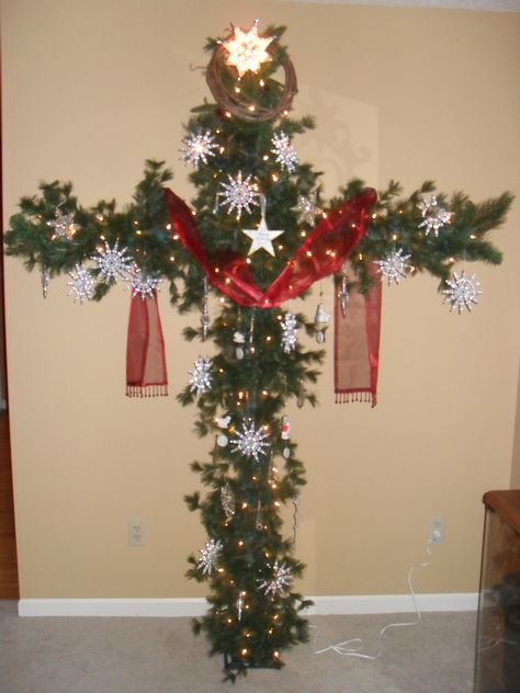 A Cross Christmas tree.  Made from PCV pipe and garland.  Red sash symbolizes our sins and the snowflakes symbolize forgivess.   Isaiah 1:18 "Those your sins be as scarlet,they shall be white as snow." Christian Decorations, Diy Crosses, Cross Wreaths, Christmas Tree Cross, Jesus Decor, Cross Tree, Church Christmas Decorations, Online Church, Cross Christmas Tree