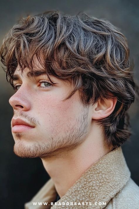 The image features a side profile of a young man with a layered shaggy men’s haircut. His hair is styled in soft, tousled layers that add depth and texture, giving it a natural, windswept appearance. The layers are longer on top, gradually tapering towards the ends, creating a dynamic and voluminous look. His facial hair is light and neatly trimmed, complementing the casual, laid-back vibe of his hairstyle. The background is blurred, ensuring that the focus remains on his men's shaggy hairstyle and its textured, layered finish. This style is perfect for those seeking a trendy yet effortless look. Mens Shag Cut, Shaggy Haircuts For Men, Men’s Longer Haircuts, Mod Hairstyle Men, Tousled Layers, New Cuts, S Haircut, Young Men Haircuts, Surfer Vibes