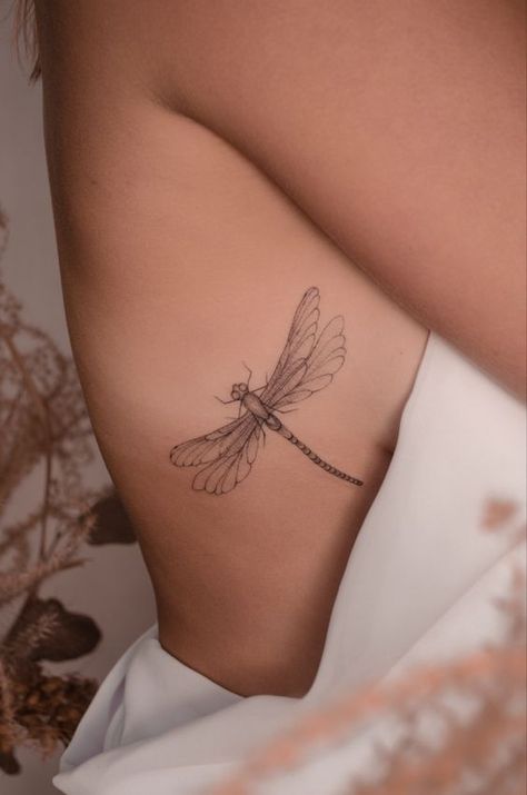 From elegance to mystique, learn about dragonfly tattoos, their symbolism, and the best designs in this article. Fine Line Back Of Arm Tattoo, Dragonfly Tattoo Ribs, Delicate Dragonfly Tattoo, Fine Line Dragonfly Tattoo, Tattoo Snake, Rib Tattoos For Women, Dragonfly Tattoo Design, Delicate Tattoo, Dragonfly Tattoo