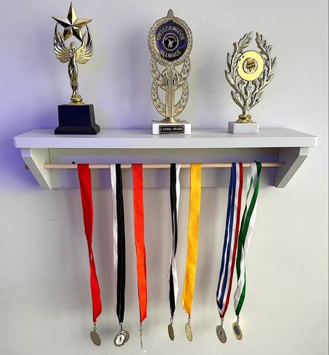 A trophy shelf and medal holder all in one. It can be personalised behind the rail too. A shelf to show of your trophies and a wooden dowel which can be pulled out to add medals to hang. Approximate dimensions: Length: 56cm Height: 13cm Length of pole available: 53cm Depth of shelf: 15.5cm Shelf For Medals, Childrens Wall Clock, Trophy Shelf, Trophy Display, Medal Holder, Trophies And Medals, Dance Gymnastics, Medal Holders, Wood Model