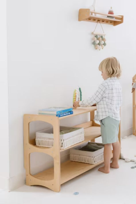 These Montessori Shelves are crafted from wood and designed for toddlers to organize their toys, books, and clothes independently. Compact and stylish, they add a functional touch to any nursery or playroom, helping to create an organized and accessible space for little ones. #MontessoriShelves #WoodenKidsFurniture #NurseryOrganizer #KidsStorage #MontessoriLifestyle Toys Shelf, Montessori Playroom Ideas, Montessori Shelves, Montessori Shelf, Kids Clothing Rack, Toddler Nursery, Wooden Nursery, Montessori Playroom, Toy Shelves