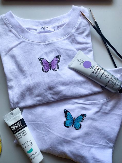 Hand painted butterflies on t shirts Tee Shirt Painting Diy, Fabric Painting On Tshirts Design, Hand Painted Butterfly On Fabric, Fabric Painting Aesthetic, Painting Shirts Aesthetic, White Shirt Diy Paint, Paint On Clothes Aesthetic, Diy Painted Tshirt Ideas, Hand Painted T-shirt