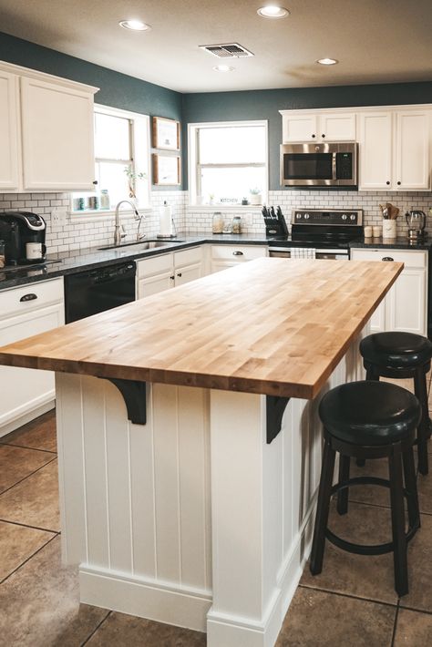 This kitchen island is so unique! I love the paneling on the kitchen island as well as the warm butcher block countertop and dark gray corbels. The colors contrast nicely with the white cabinets, subway tile, and stainless steel appliances. #kitchentransformation #diyproject #subwaytile #diykitchen Butcher Blocks, Rayong, Farmhouse Kitchen Island, Wood Kitchen Island, Diy Kitchen Renovation, Classic Kitchen, Subway Tiles, Kitchen Island Design, Kitchen Decorating