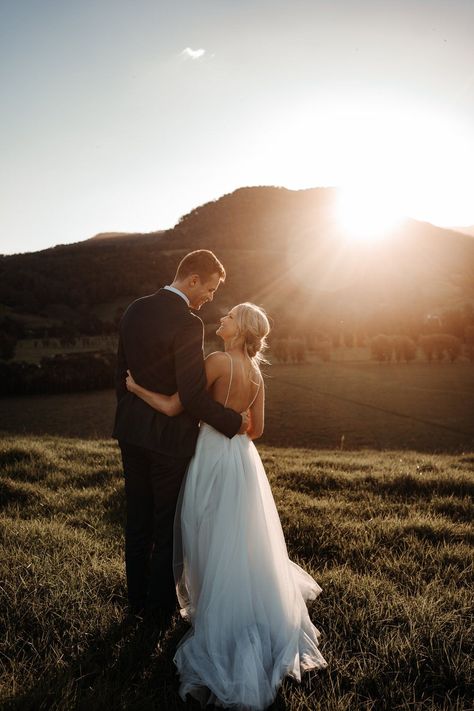 Couple looking at each other with the sun setting behind the mountains in front of them. If you want to plan your wedding for sunset, check out this guide! Couple Looking At Each Other, Outdoor Wedding Pictures, Mountain Wedding Photos, Sunset Wedding Photos, Looking At Each Other, Barn Wedding Photos, Wedding Portrait Poses, Wedding Couple Photos, Wedding Picture Poses