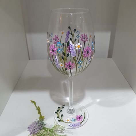 A beautiful hand painted wildflower wine glass with pinks, lilacs white and blues painted all around the glass. Some lovely tiny glitter dots on the blue flowers  really makes this glass special. Wine Glass Flower Painting, Painted Flowers On Glass Bottles, Cute Painted Glasses, Painted Glass Pitcher, Glass Painting Designs Flowers, Hand Painted Gin Glasses, Wine Glass Painting Ideas Flowers, Floral Glass Painting, Flower Painted Wine Glasses