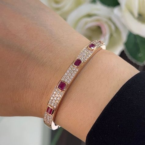 This bangle bracelet is a stunning testament to elegance and sophistication, crafted from lustrous 18 karat rose gold to exude warmth and charm. Adorning the bracelet are a mesmerizing array of natural diamonds and radiant emerald-cut rubies, creating a captivating contrast of sparkle and color. The bracelet features round-cut diamonds totaling 1.63 carats, boasting a remarkable G color and VS2 clarity. Set in a combination of pave and bezel settings, the diamonds shimmer with brilliance and fire, adding a touch of glamour to the design. Interspersed among the diamonds are enchanting emerald-cut rubies totaling 1.42 carats, set in bezel settings to accentuate their vibrant red hue. Their exquisite beauty adds a rich and captivating dimension to the bracelet, creating a striking harmony wit Ruby Bangles, Diamond Bangles, Diamond Bracelet Design, Ruby Bracelet, Diamond Bangles Bracelet, Bangles Jewelry Designs, Gold Jewelry Indian, Jewelry Lookbook, Bangle Designs