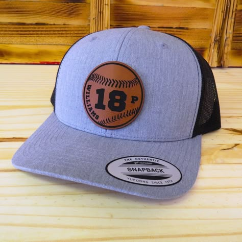 Support your son, daughter, grand daughter, grandson, or favorite college / pro player on their baseball teams with this laser engraved player name and number leather patch hat! The patch is a baseball with your custom player name and number with optional position abbreviation etched inside of it.  The hats are the popular trucker style snapback that look great and are available in several colors - see available colors.  Hat Details:  SIZE - Adult and youth sizes with snap closure. Adult - 6 5/8 - 7 5/8 | Youth - 6 3/8 - 7 1/8 DESIGN - Custom laser etched baseball patch with your name and number and optional position. MATERIAL - Vegan Friendly Leather Patch (Leatherette).  SHIPS - In a full size box to keep your new hat in perfect condition As this item is a custom made item, refunds and r Baseball Hats Custom, Hat Patches Design, Leather Hat Patch Ideas, Leather Patch Hat Ideas, Leather Patch Hat Design, Leather Hat Patch Designs, Leather Patches On Hats, Patch Hats Baseball Caps, Baseball Cap With Leather Patch