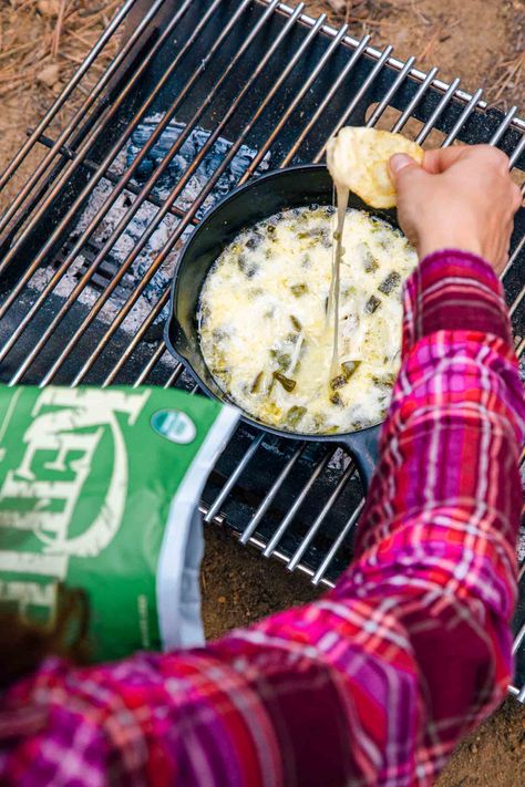 Dipping a chip into a skillet of queso fundido on a campfire. Good Dips, Hand Held Snacks, Camping Appetizers, Family Camping Meals, Campfire Snacks, Dip Ideas, Butter Biscuit, Camping Snacks, Bag Of Chips