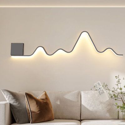 The wall sconce lighting fixture designed in a unique wavy and linear structure shape, add more fashion elements to your house, blends with most types of home decoration style. This modern wall sconces have a memory function. When you turn it on, it will maintain the lighting mode you turned off last time. And its light color and brightness can be adjusted. | Wrought Studio™ Heidamos 1 - Light 43.3" Aluminum LED Flush Mounted Sconce Metal in Black / White | 7.08 H x 43.3 W in | Wayfair Modern Ambient Lighting, Wall Art Lighting Ideas, Wall Lights Behind Sofa, Dining Room Wall Lighting, Creative Bedroom Lighting, Lights Behind Couch, Hallway Wall Decor Modern, Led Strip Lighting Ideas Living Rooms, Wall Led Light Decor