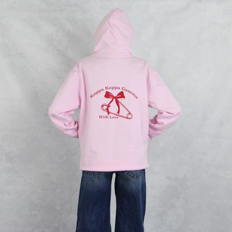 Kappa Kappa Gamma hoodie in pink with the new, trending bow and safety pin design. With a practical pouch pocket and cute logo, it's the unisex sorority sweatshirt to start your new school year. This pink Kappa hoodie has red print on the front and back. The front design is a bow with Kappa since 1870 and the back has a bow, safety pin and Kappa Kappa Gamma With Love. A new school year means new designs and this unisex Kappa Kappa Gamma hooded sweatshirt is part of our new 2024/2025 collection. This super cute sorority sweatshirts unisex fit is the ultimate in warmth, comfort and sorority fashion. Wear this sorority hoodie top with everything from shorts to jeans or leggings. Kappa Kappa Gamma Hoodie Sizing Model is 5'9", size 0/2, and wearing size M Kappa Hoodie Technical Details  - 8.5 o Kappa Hoodie, Safety Pin Design, Sorority Fashion, Cute Logo, Sorority Sweatshirts, Kappa Kappa Gamma, Gamma Phi Beta, Kappa Alpha Theta, Pin Design