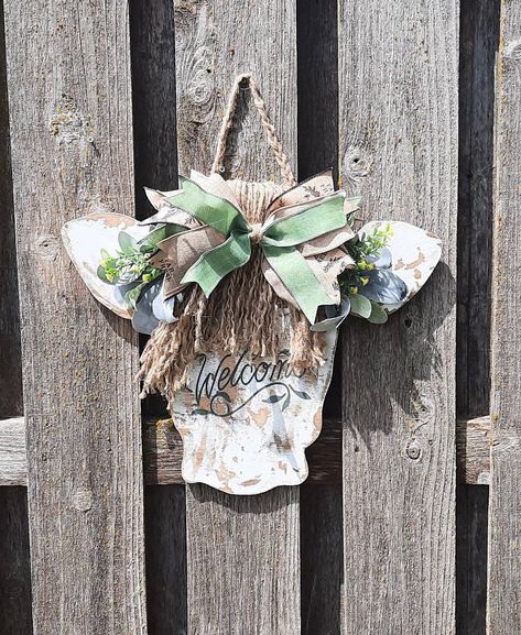 "Cow Head Door Hanger | Front Door Decor | Highland Cow Decor | Farmhouse Decor | Rustic Decor  Bless Our Home Sign | Distressed Outdoor Sign Details:  * In stock and ready to ship  * Handmade, painted on real wood  * 16\" tall, 19\"wide, 1/2\"  thick  * Felt pads included to prevent scratching of your door/wall  * Sealed with outdoor Spar Urethane for long life  * Bow / greenery are secured with glue and staples  * Attached rope hanger Due to the natue of wood, some wood grain, distressing, tex Farmhouse Highland Cow Decor, Cow Door Hanger Wooden, Highland Cow Door Hanger, Bless Our Home Sign, Cow Head Door Hanger, Highland Cow Decor, Cow Door Hanger, Our Home Sign, Spar Urethane